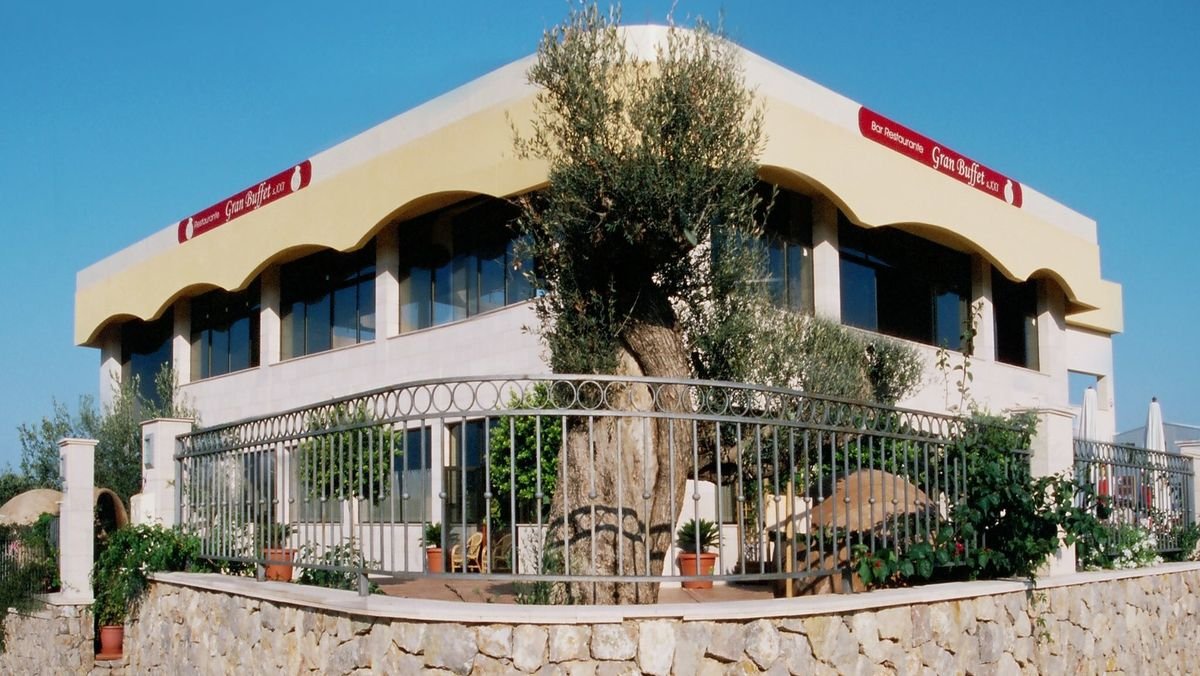 Fachada del Gran Buffet s.XXI con su terraza y un gran olivo delante